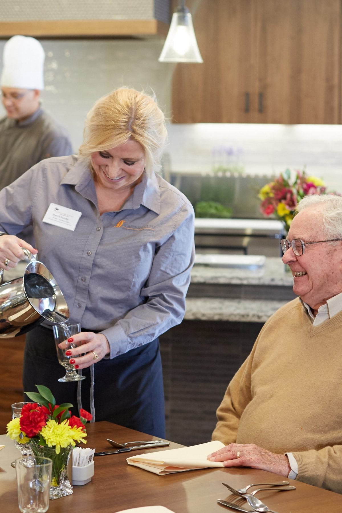 Someren Glen Senior Living Community in Centennial, CO - short term rehab neighborhood team member pouring water for older couple dining portrait